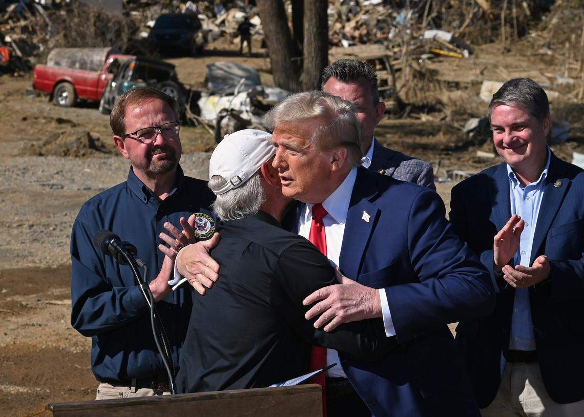 Former President Donald J. Trump, right, is hugged by a local Swannanoa, NC business owner, left, who led Monday’s group in prayer during Trump’s stop in the area to see the damage caused by Hurricane Helene.