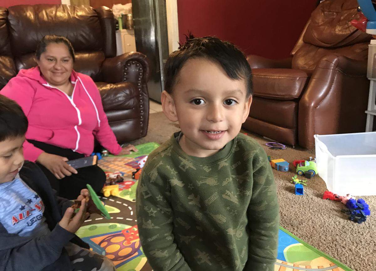 Nelson Moran, age 3, plays with cars on the floor of his home while his mom, Imelda Moran, looks on. Nelson has autism, and on his Christmas list are a weighted blanket and a tablet to load apps for kids with autism.
