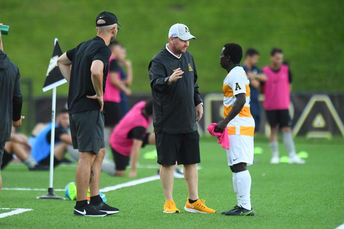 Appalachian State men’s soccer coach Jason O’Keefe (center) talks to forward Kelvin Mulinya (right) during a 2019 home game in Boone. O’Keefe coached App State for four years until the program was disbanded in May 2020 for cost-cutting reasons.