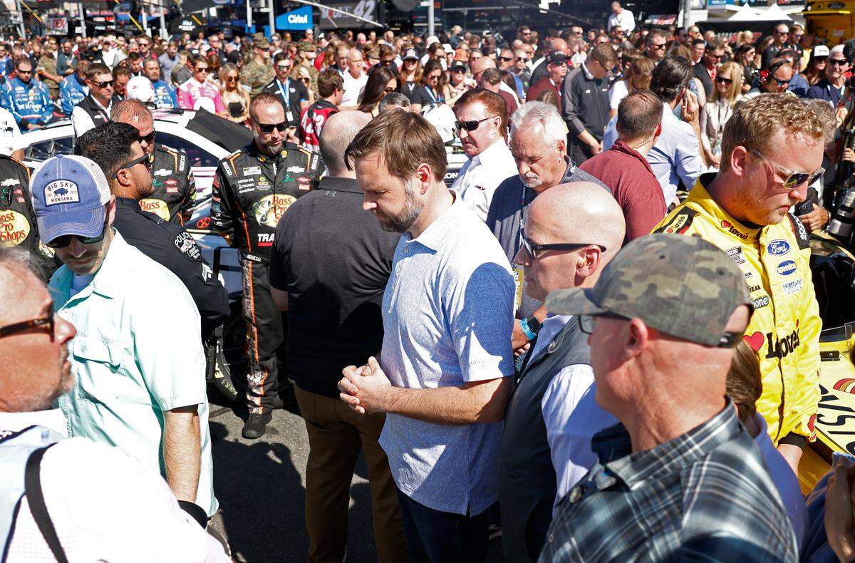 Vice Presidential Nominee Senator JD Vance, center, clasps his hands in prayer as the invocation is given prior to the running of the Bank of America Roval 400 at Charlotte Motor Speedway in Concord, NC on Sunday, October 13, 2024.
