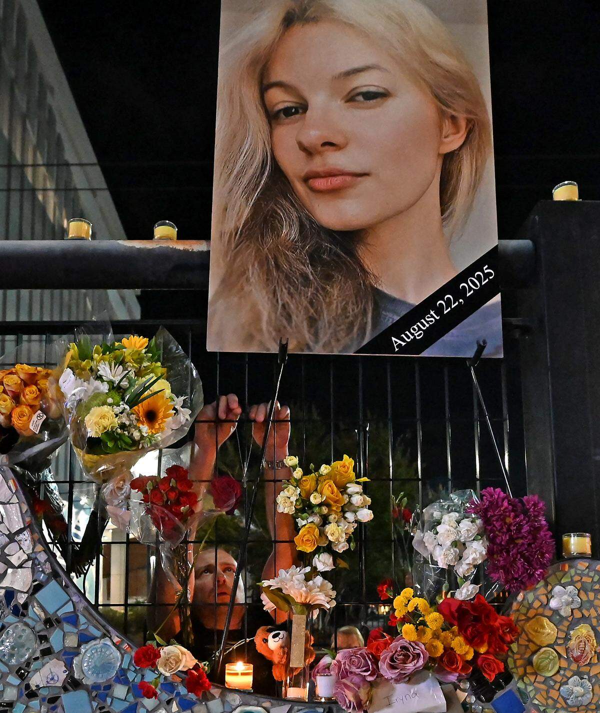 A man places flowers in a makeshift memorial for Iryna Zarutska at the East/West Boulevard light rail station on Monday.