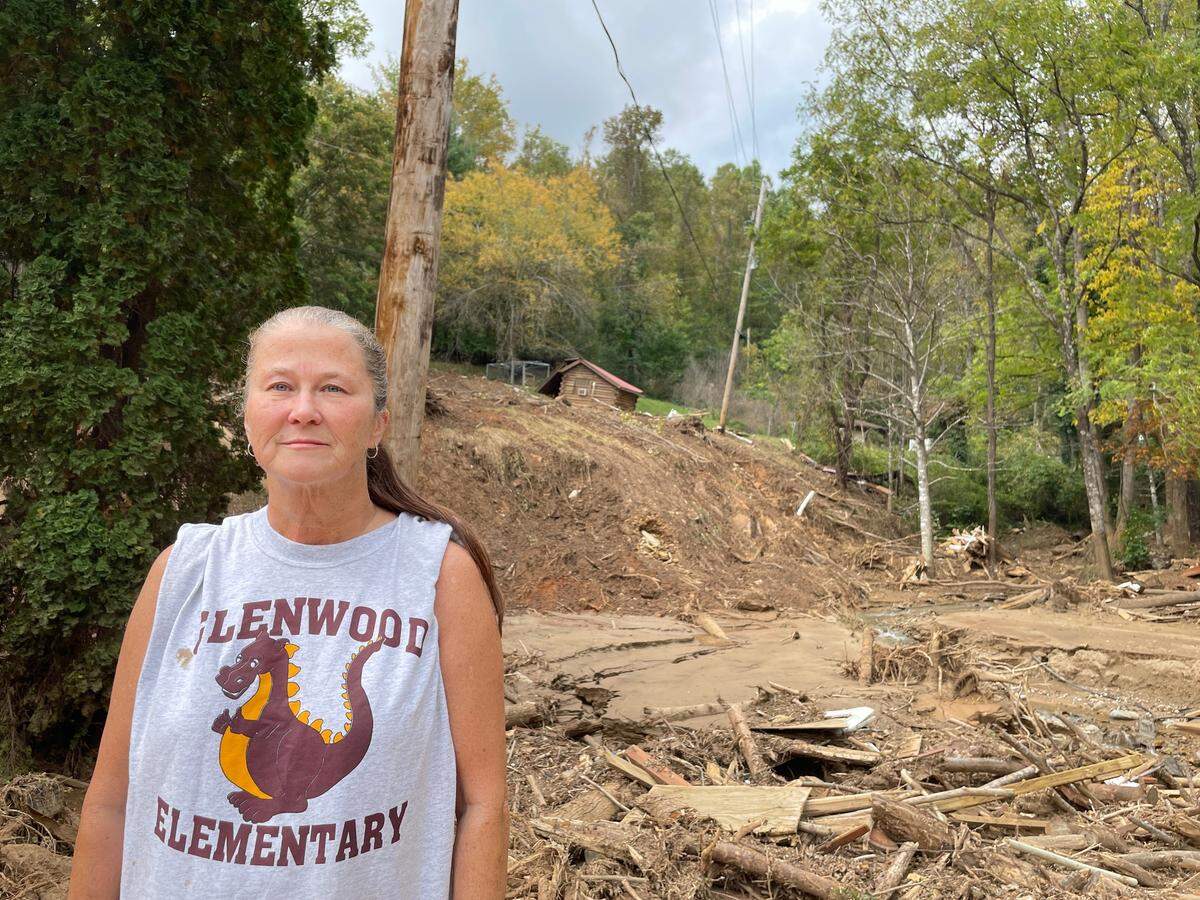 Karen Hollifield, 57, stands near the aftermath of a mudslide on Friday, Oct. 4, 2024, one week after remnants of Hurricane Helene tattered Western North Carolina. A cabin her dad built sits above. It’s one of the few structures in her area left standing.