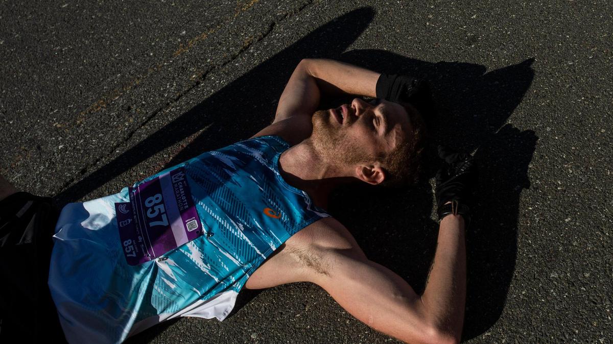 Adam Jones lies down in exhaustion after crossing the finish line for the first place at the Charlotte Marathon on Saturday, November 13, 2021 in Charlotte, NC. This was Jones’ first marathon.