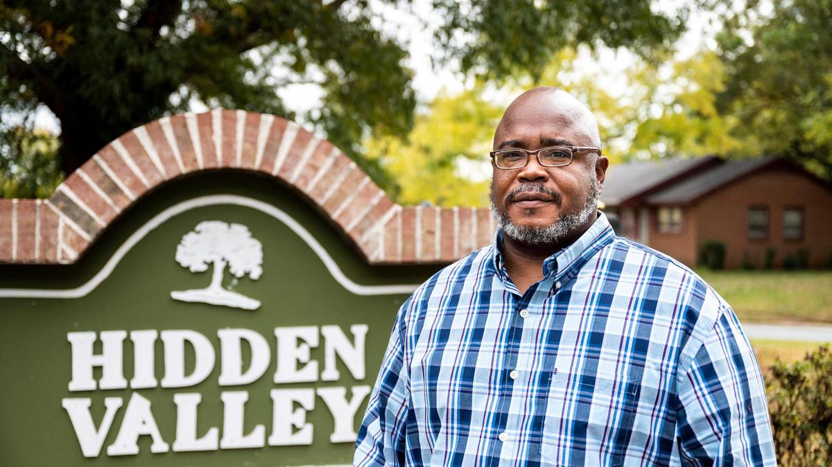 Charles Robinson, vice president of the Hidden Valley homeowners association, stands in front of a neighborhood sign on Nov. 3, 2021 that was hand-carved by a shop teacher in the community. “This is what we do in our community,” Robinson said. “We make sure we take care of what we have; it’s not much, but it’s ours.”