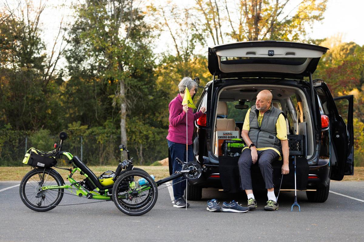 Denise Sussman, left, helps her husband Alan Sussman, prepare for a bike ride on the Little Sugar Creek Greenway through Park Road Park in Charlotte. Sussman is back riding a recumbent bicycle after being severely hurt seven years ago while riding a bike in Charlotte.