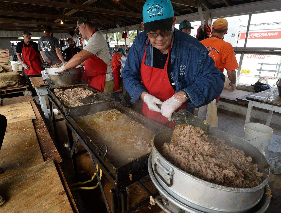 Andy Stiffel, back left, and Ned Baker cook and dish up barbecue  at the Mallard Creek Barbecue. The tradition is ending after 93 years, organizers said on Wednesday, Oct. 1, 2025.