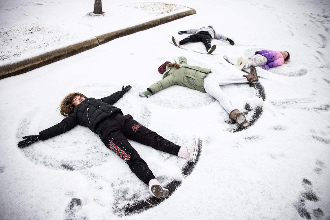 Breille Fernandez, left, Alexis Collins, Kylie, Fernandez and Faith Collins, of Ocala, Florida, make snow angels in a parking lot during winter storm in Charlotte in January 2022. North Carolina could see a cold, snowy winter with below average temperatures, according to The Old Farmers’ Almanac winter weather forecast for 2025.