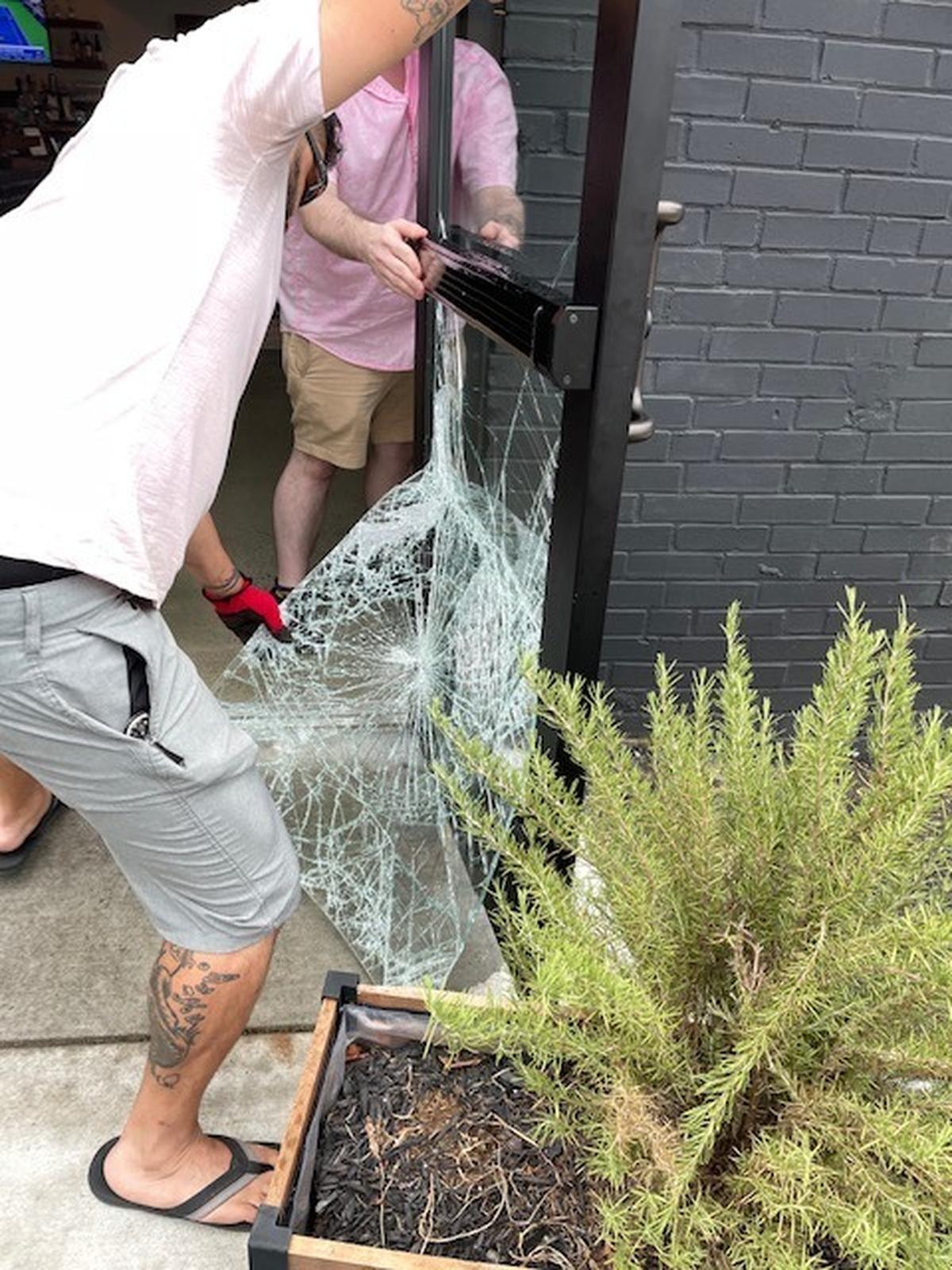 Workers remove a damaged window from a door at The Exchange at 36th specialty grocery store in the NoDa neighborhood in Charlotte, NC, on Monday, September 6, 2021. Charlotte-Mecklenburg police say Malek Moore broke into the store house after killing Gabryelle Allnut, an artist from New Orleans.