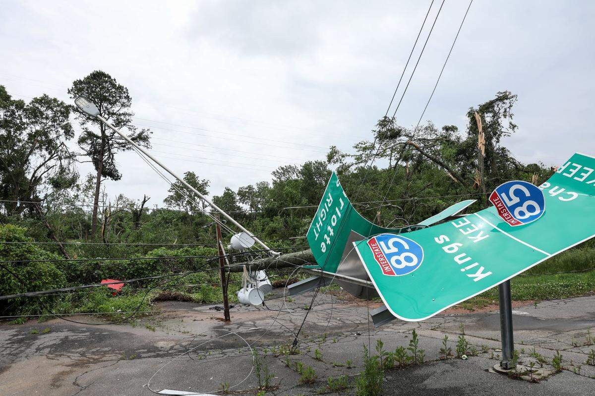 The exit sign onto I-85 is tangled with electrical wires from a downed utility pole along North Chester Street in Gastonia, N.C., on Thursday, May 9, 2024. Storms tore through the area yesterday causing property damage and causing power outages.