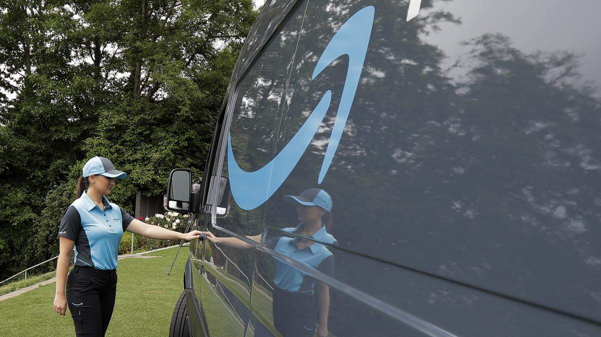 In this June 27, 2018, file photo, Parisa Sadrzadeh, a senior manager of logistics for Amazon.com, opens the door of an Amazon-branded delivery van at the request of a photographer in Seattle, following a media event for Amazon to announce a new program that lets entrepreneurs around the country launch businesses that deliver Amazon packages. Amazon says it has ordered 20,000 vans for its new delivery program. The online retailer says “tens of thousands” of individuals have applied for the program, and it had to up its van order to 20,000 from 4,500.