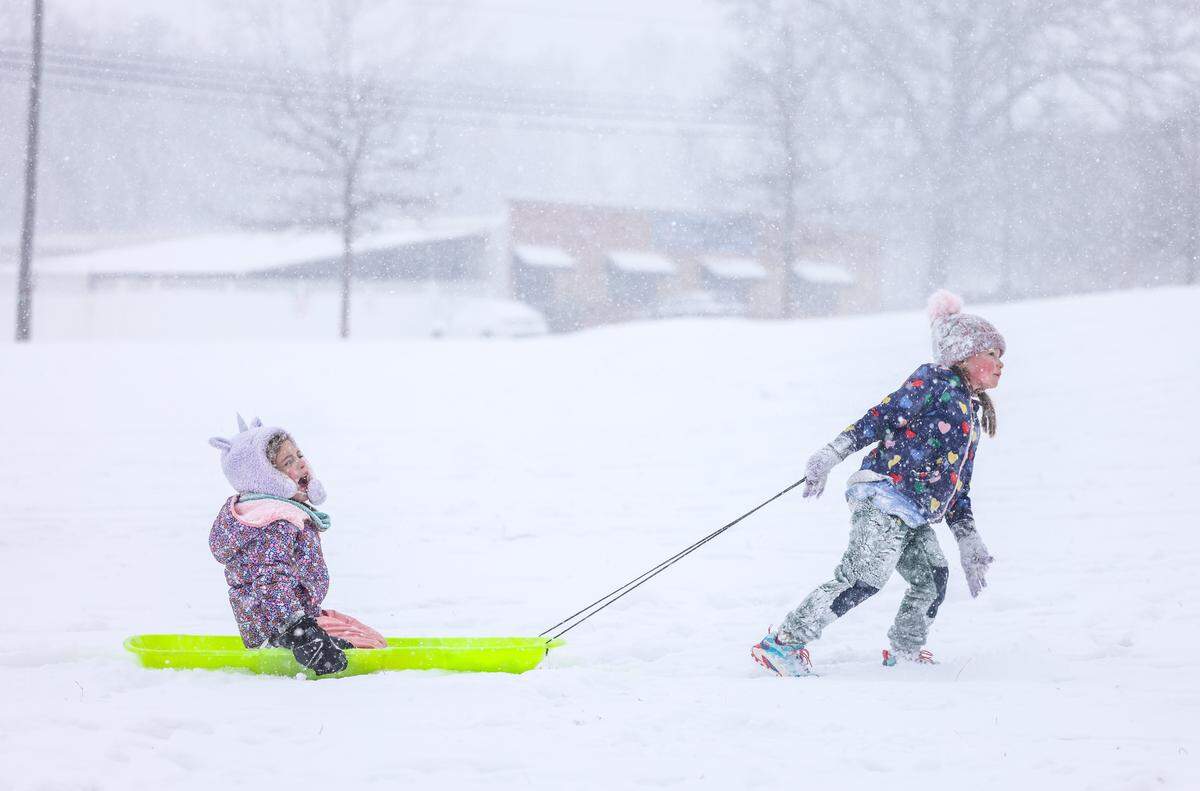 A little girl pulls another girl on a sled in Cordelia Park in Charlotte, N.C., on Saturday, January 31, 2026.