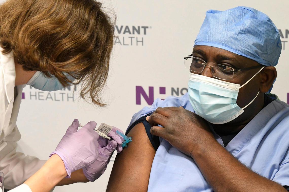 Dr. Samuel Dartey-Hayford receives the first shot from a delivery of the COVID-19 vaccine to Novant Health in Charlotte. Pharmacy resident Kayla Askey administered the vaccine at Novant Health Presbyterian Medical Center on Thursday, December 17, 2020.