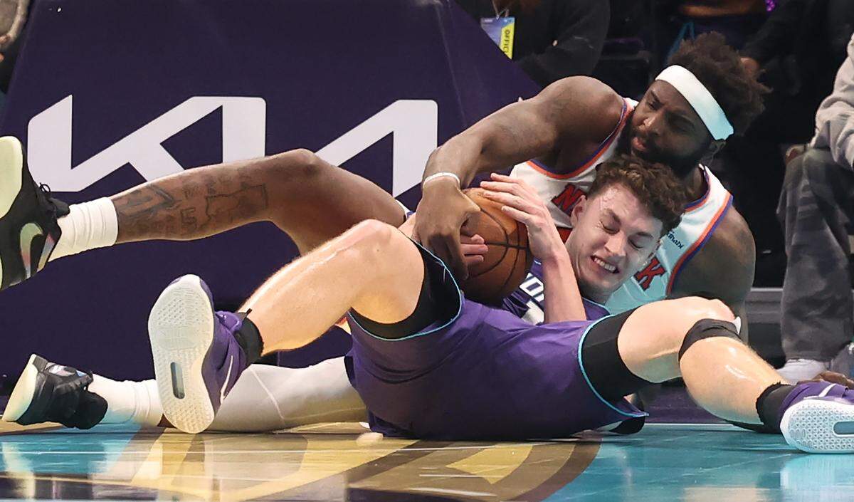 Charlotte Hornets center Ryan Kalkbrenner, front, fights to maintain control of a loose ball with New York Knicks center Mitchell Robinson during action at Spectrum Center in Charlotte, North Carolina, on Wednesday, Nov. 26, 2025. The Knicks defeated the Hornets 129-101. 