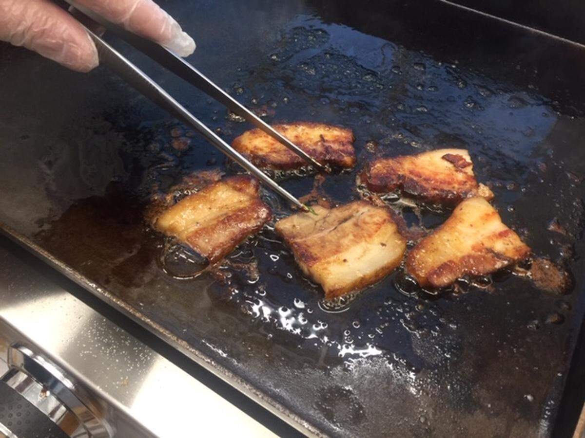 Chef Larry Scheiber of the Moffett Group fries pork belly for samples of the steamed buns he’ll serve at Bao & Broth at Optimist Hall.