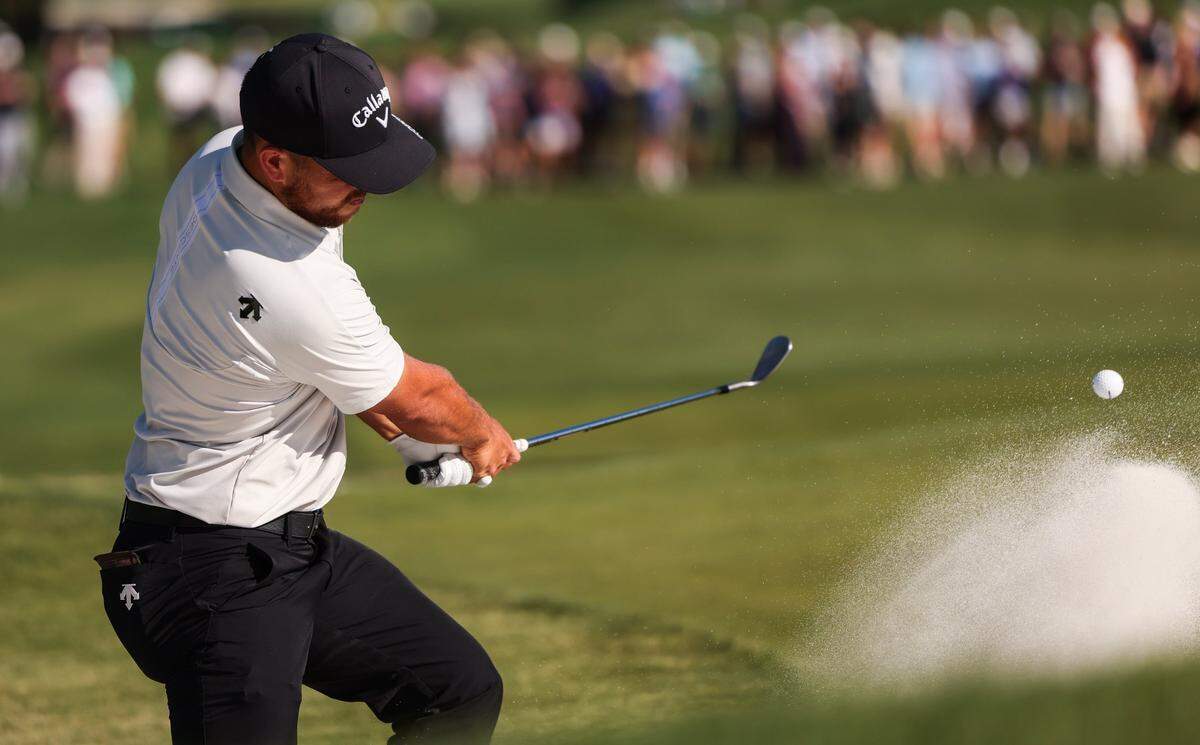 Xander Schauffele hits from a bunker on the 18th hole during round three of the Wells Fargo Championship at Quail Hollow Club in Charlotte, N.C., on Saturday, May 11, 2024.
