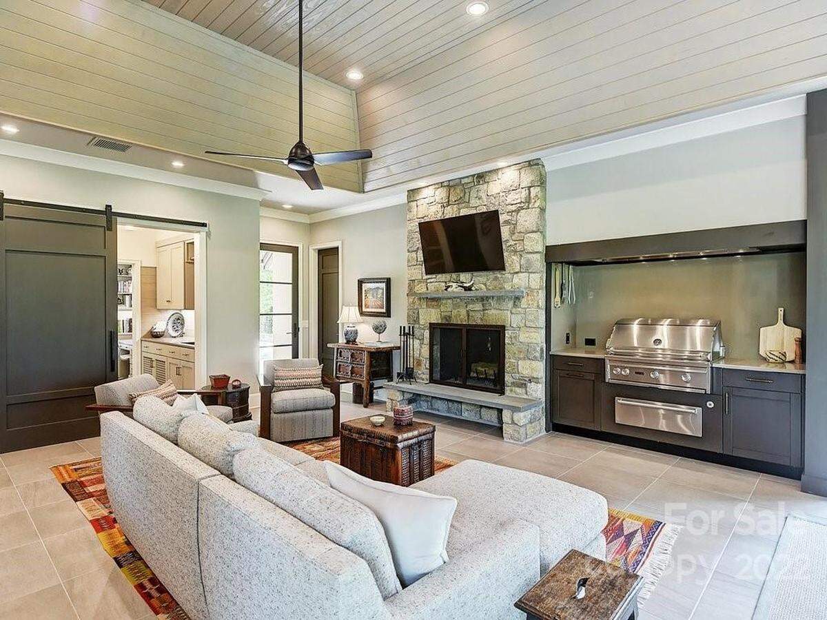 The “living porch” area of the home features a stone fireplace, a grill, and LaCantina Doors that open to the lake. The porch includes retractable screens that can be lowered when the the doors are open.