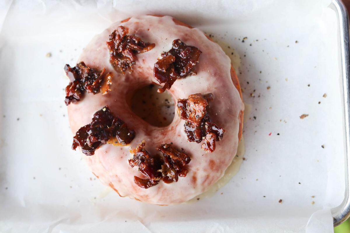 The Bourbon Candied Bacon Doughnut at Sugar Donuts is covered in a handmade bourbon glaze and topped with peppered honey-bourbon bacon.
