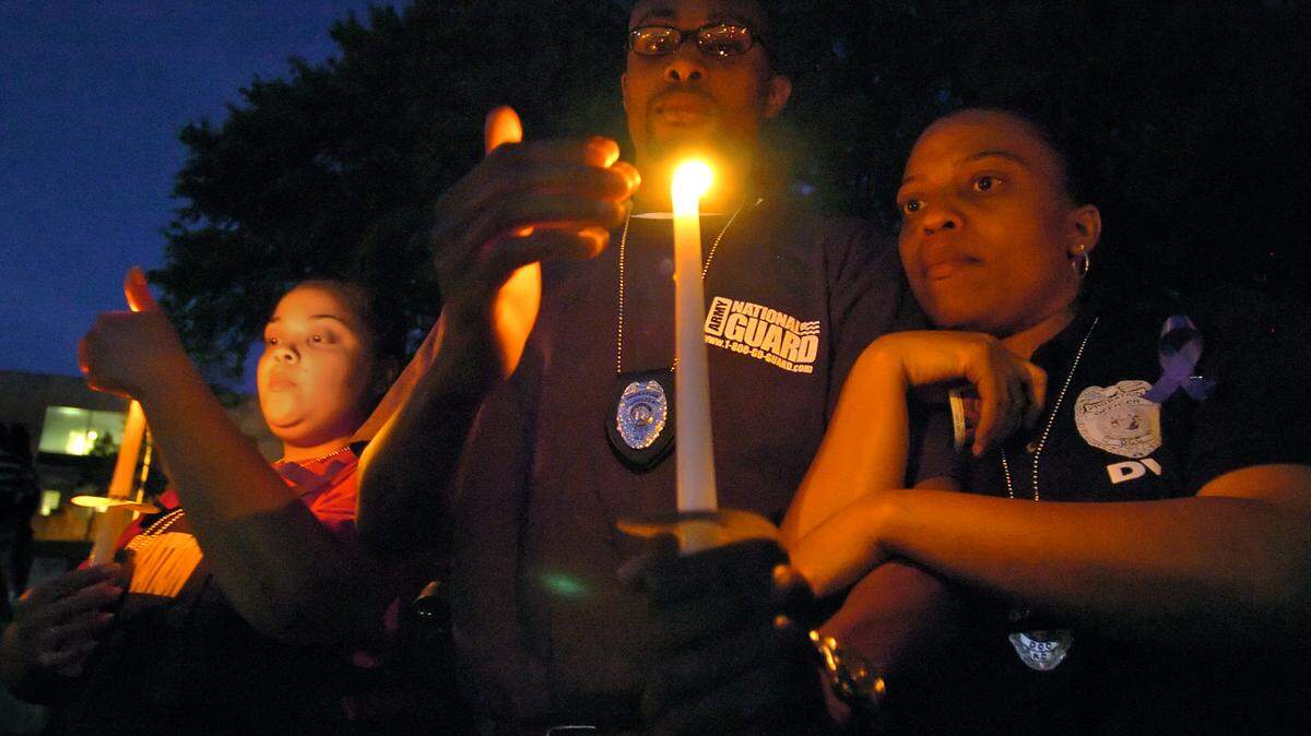 North Carolina Department of Corrections Probation Officers Sherri Sullivan, David Gary and LaTonya Lynch hold candles as Mothers of Murdered Offspring and Footprints Ministries sponsor a community candlelight memorial service at Marshall Park in memory of slain Charlotte Mecklenburg police officers Sean Clark and Jeff Shelton on Wednesday, April 4, 2007.