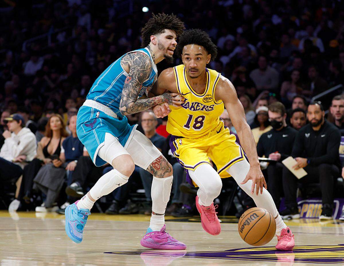 Kobe Bufkin of the Los Angeles Lakers drives past LaMelo Ball #1 of the Charlotte Hornets during the first half at Crypto.com Arena.