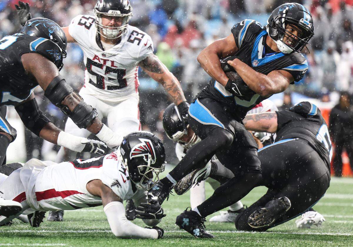 Carolina Panthers running back Chuba Hubbard, right avoids a tackle by Atlanta Falcons safety DeMarcco Hellams at the Bank of America Stadium in Charlotte, N.C., on Sunday, December 17, 2023.