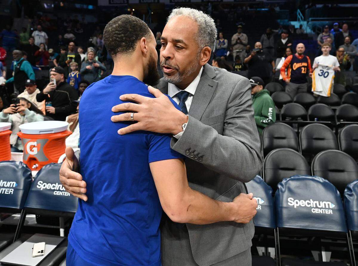 Golden State Warriors and former Davidson Wildcats star Steph Curry, left, hugs his father Dell Curry prior to the team's game against the Charlotte Hornets at Spectrum Center in Charlotte on March 3, 2025.