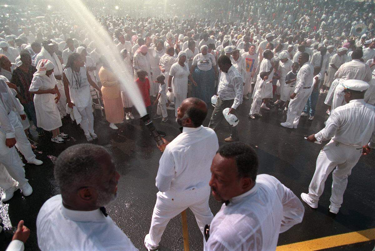 10/11/98 United House of Prayer for All People church leaders spray water from a fire hose onto thousands of believers Sunday as they were baptized in the parking lot of the church’s temporary home.
