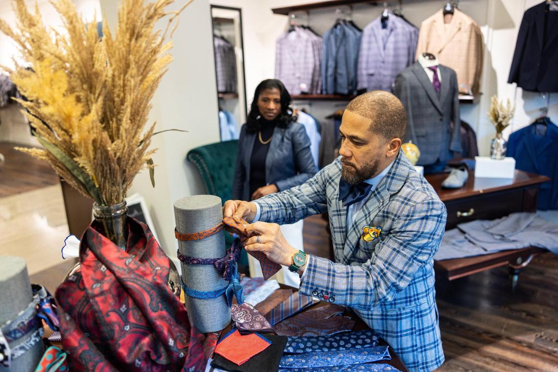 Darrius Williams adds bowties to a display as his wife, Dana Cathey-Williams, watches March 13, 2024, at their Northlake Mall store, which opened in the fall.