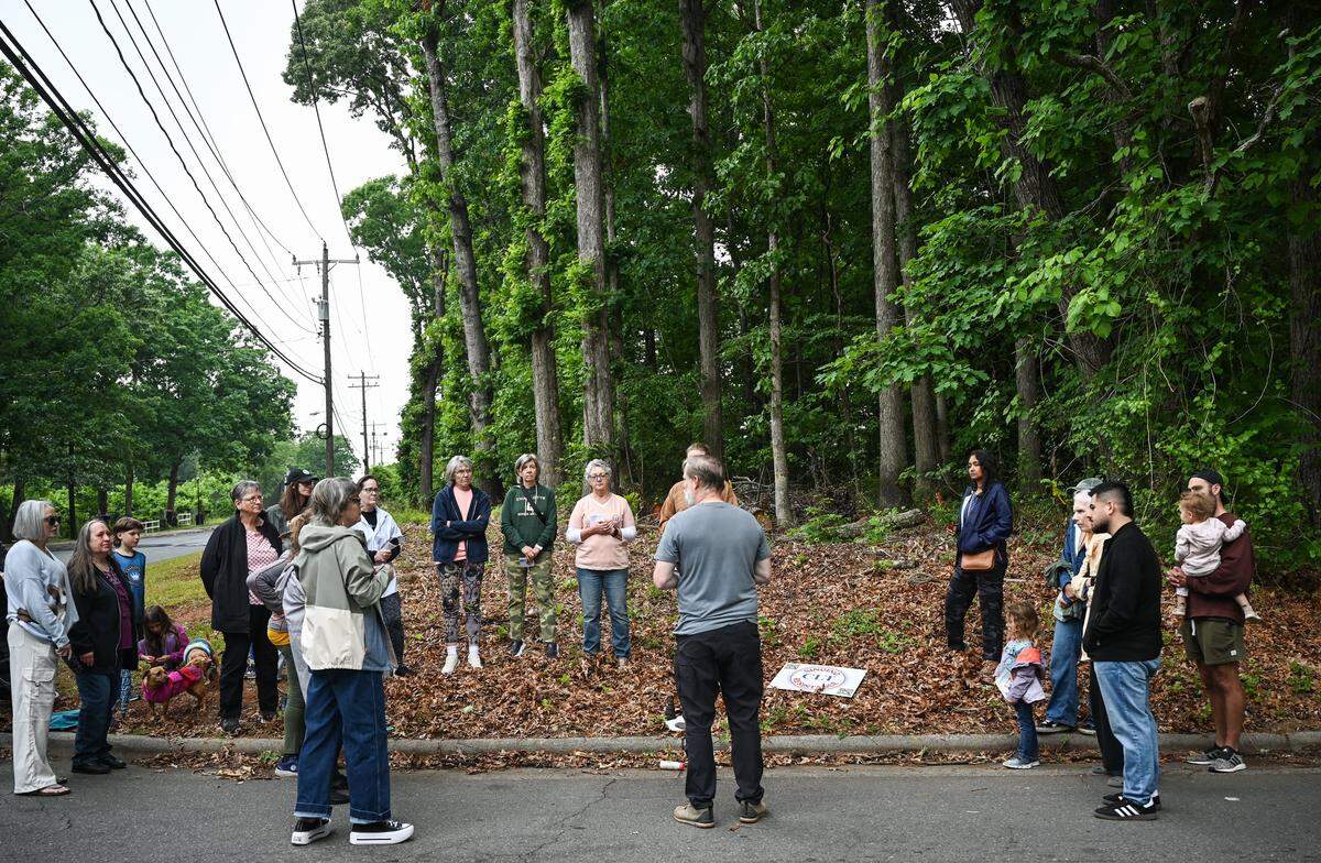 Residents of an east Charlotte neighborhood gather at the corner of Mayberry Lane and Wilora Lake Road, in front of a 6.6-acre wooded area the city approved a rezoning request for that will replace the trees with new housing, to hold a memorial service to mourn the eventual loss of the trees.