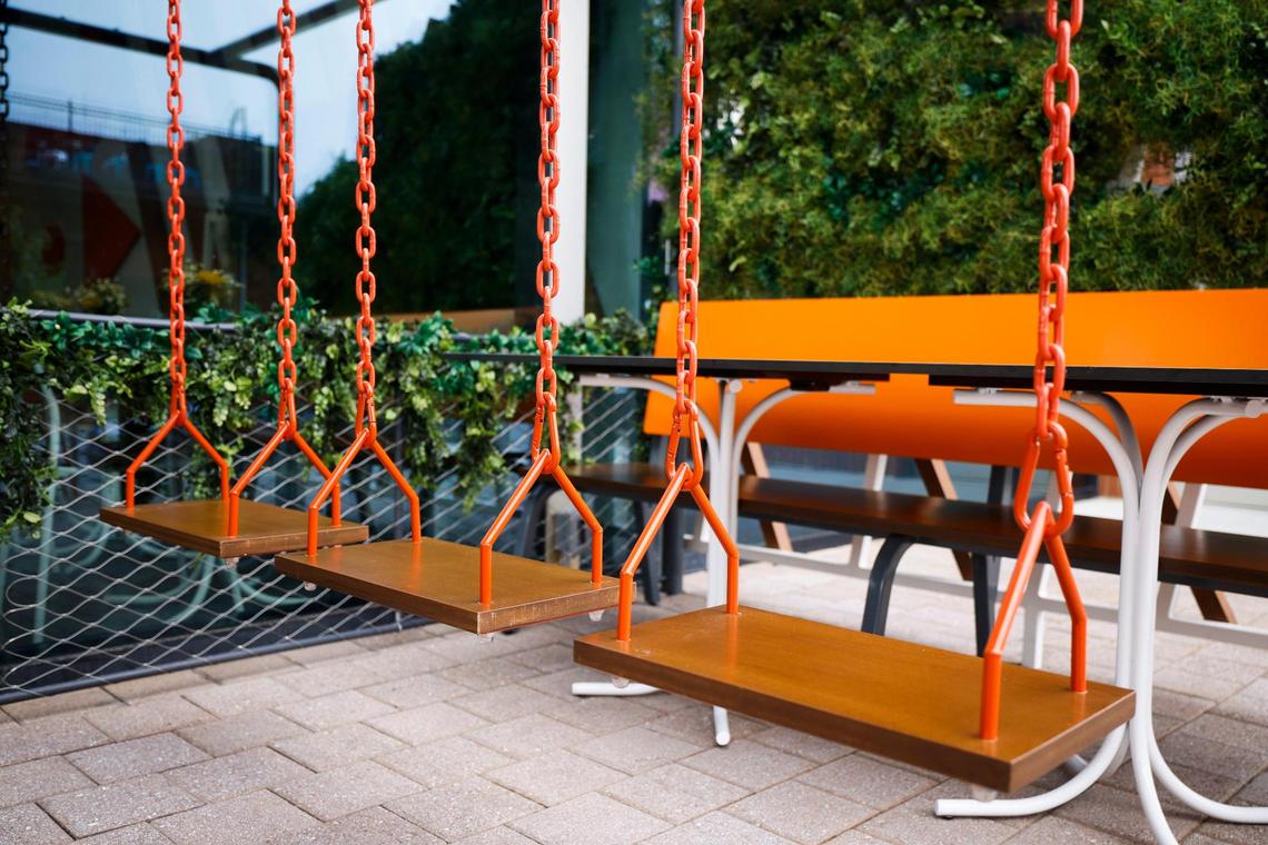Swings and benches sit along South Tryon Street at Summerbird, fast-casual chicken sandwich and salad restaurant at RailYard in South End.