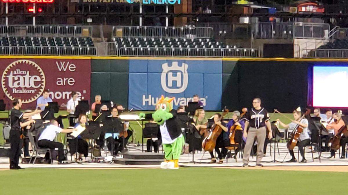 Homer the Dragon, the Charlotte Knights’ mascot, conducts the Charlotte Symphony Orchestra during a patriotic-themed performance at Truist Field on Friday, June 25, 2021.