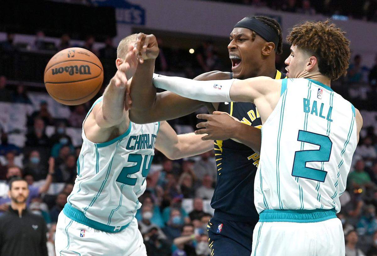 Hornets center Mason Plumlee, left, and guard LaMelo Ball, right, knock the ball away from Indiana Pacers center Myles Turner at Spectrum Center on Oct. 20, 2021.