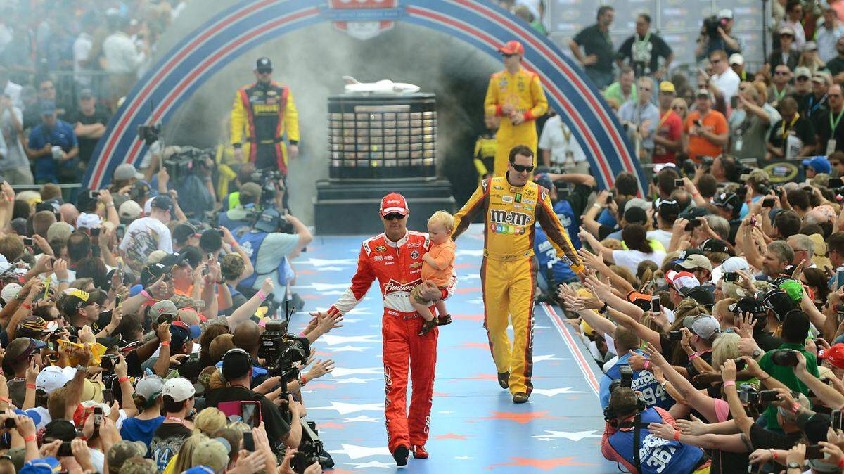 NASCAR Sprint Cup Series drivers Kevin Harvick, carrying his son Keelan, and Kyle Busch (18) are introduced during driver introductions for the Daytona 500 at Daytona International Speedway on Sunday, February 23, 2014. The race was stopped due to rain. 