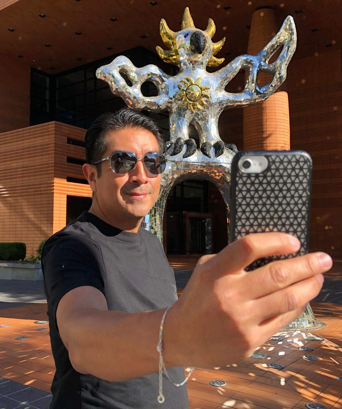 Norberto Tipei takes a selfie with the Firebird sculpture outside the Bechtler Museum.
