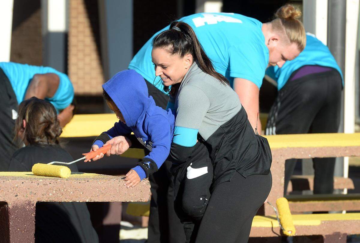 Nicole Tepper gets an assist painting a table from Kai Brown, 2 yrs, at Harding University in Charlotte, NC on Tuesday, November 16, 2021. Tepper was joined by several Carolina Panthers players in an effort to help make improvements around the campus for students.