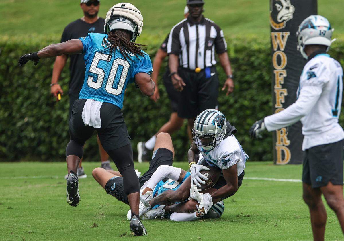 Panthers wide receiver Shi Smith, center, is dragged to the ground by safety Kenny Robinson during the Back Together practice in Gibbs Stadium at Wofford College on Saturday, July 30, 2022 in Spartanburg, SC.