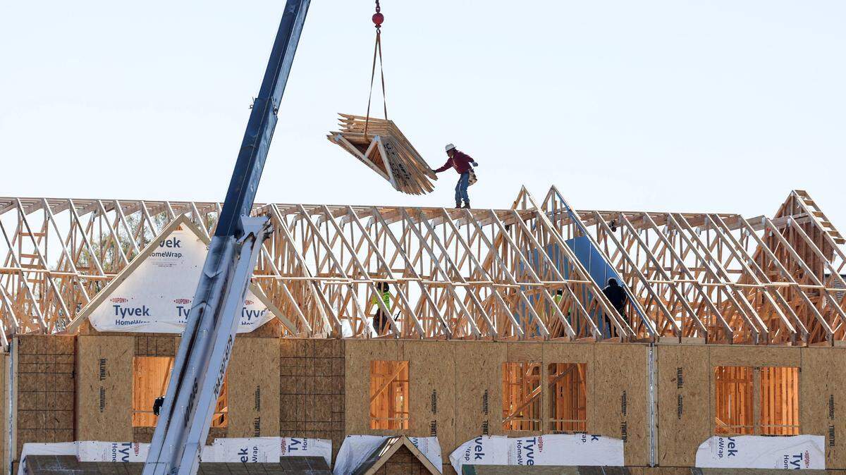 A construction worker reaches for a load from a crane at the construction site in 2023.