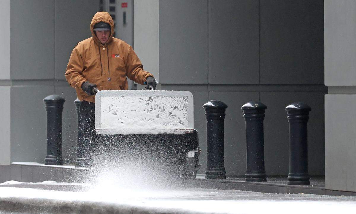 A worker clears the sidewalk along 3rd Street in uptown Charlotte, NC after a wintry mix of ice, freezing rain and light arrived in the Charlotte, NC area on Sunday, January 25, 2026.