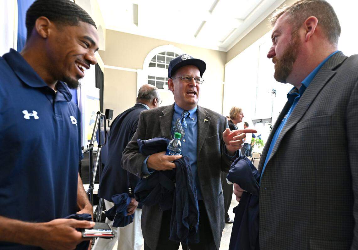 ASUN Conference Commissioner Ted Gumbart, center, speaks with Queens University’s Kenny Dye, left and head basketball coach Grant Leonard, right, after formally welcoming Queens University of Charlotte into the league on Tuesday, May 10, 2022. The announcement moves the Royals into NCAA Division 1 competition. Dye is a point guard on the Royals basketball team.