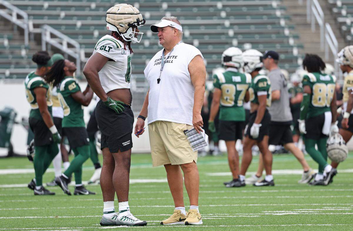 Charlotte 49ers head football coach Biff Poggi, right, speaks with defensive lineman Eyabi Okie-Anoma, left, during the team’s first practice on Friday, August 4, 2023.