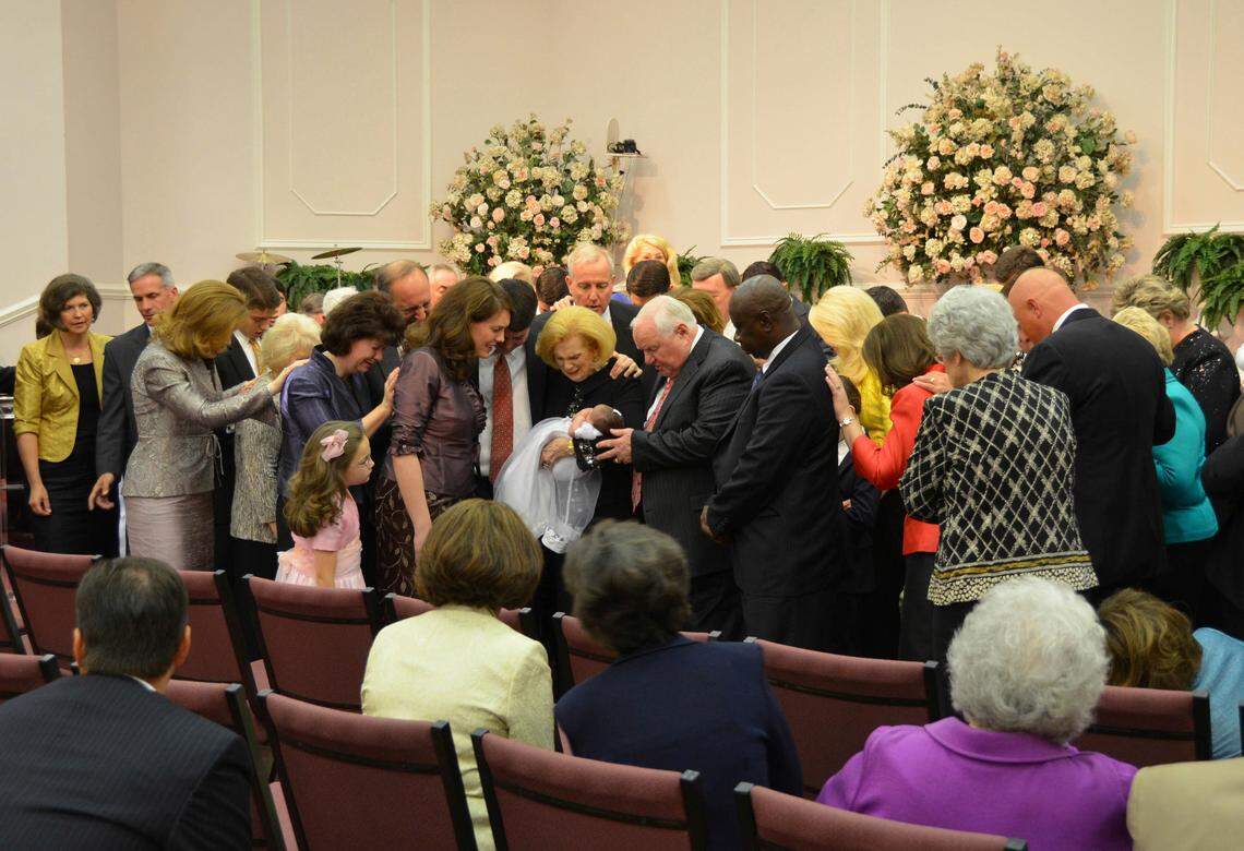 In this 2012 photo provided by a former member of the church, Word of Faith Fellowship leader Jane Whaley, center, holds a baby with others during a church ceremony in Spindale, North Carolina. On Thursday, Kent Covington of Rutherfordton, a top minister in the Word of Faith Fellowship church, was indicted by a federal grand jury on a charge of conspiracy to commit wire fraud, in what prosecutors called an unemployment insurance benefits scheme..