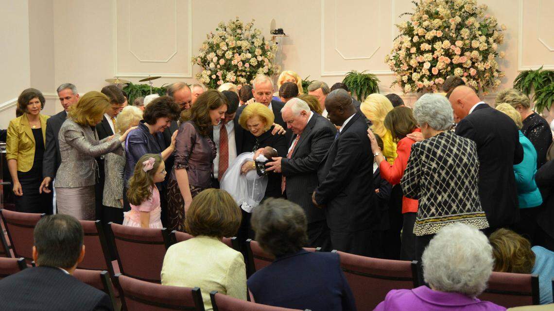In this 2012 photo provided by a former member of the church, Word of Faith Fellowship leader Jane Whaley, center, holds a baby with others during a church ceremony in Spindale, North Carolina. On Thursday, Kent Covington of Rutherfordton, a top minister in the Word of Faith Fellowship church, was indicted by a federal grand jury on a charge of conspiracy to commit wire fraud, in what prosecutors called an unemployment insurance benefits scheme..
