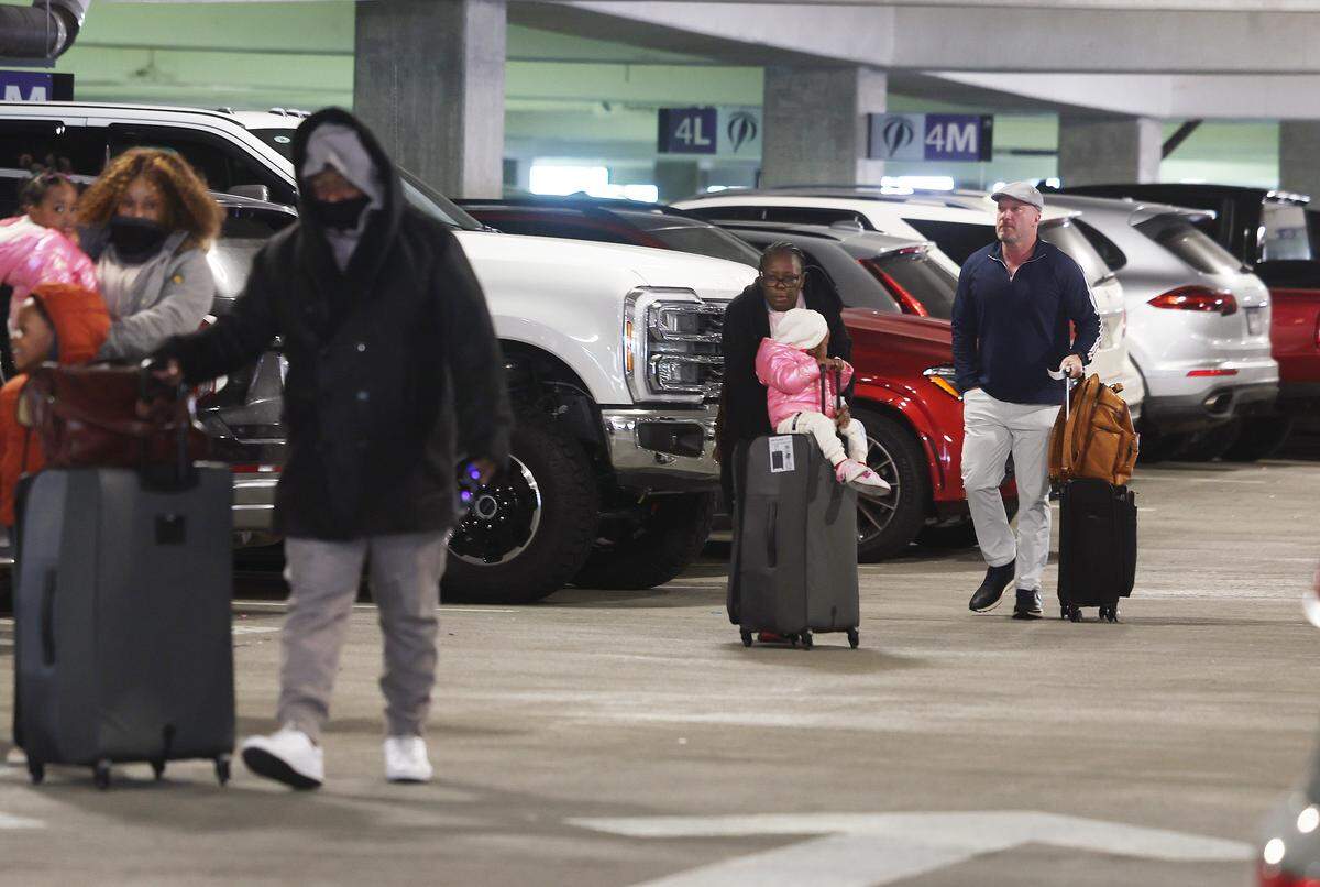 Travelers walk to the airport from the daily parking lot Wednesday, Jan. 28, 2028 at Charlotte Douglas International Airport. The airport is raising parking fees on March 1. 