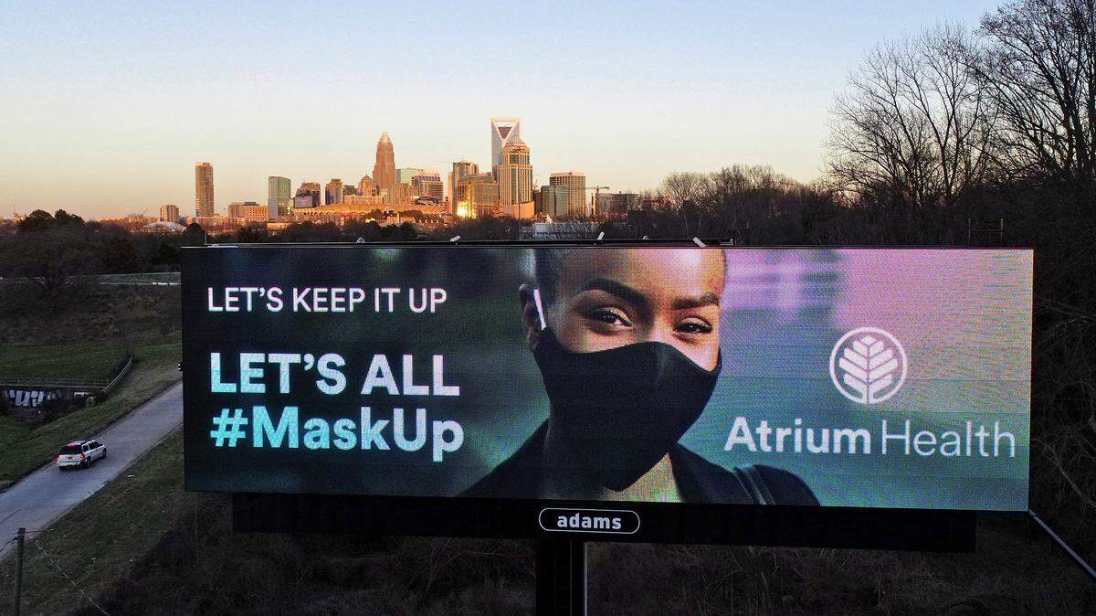 The skyline of Charlotte, NC provides the backdrop for an Atrium Health billboard encouraging travelers to keep wearing their masks along Wilkinson Boulevard on March 3, 2021.