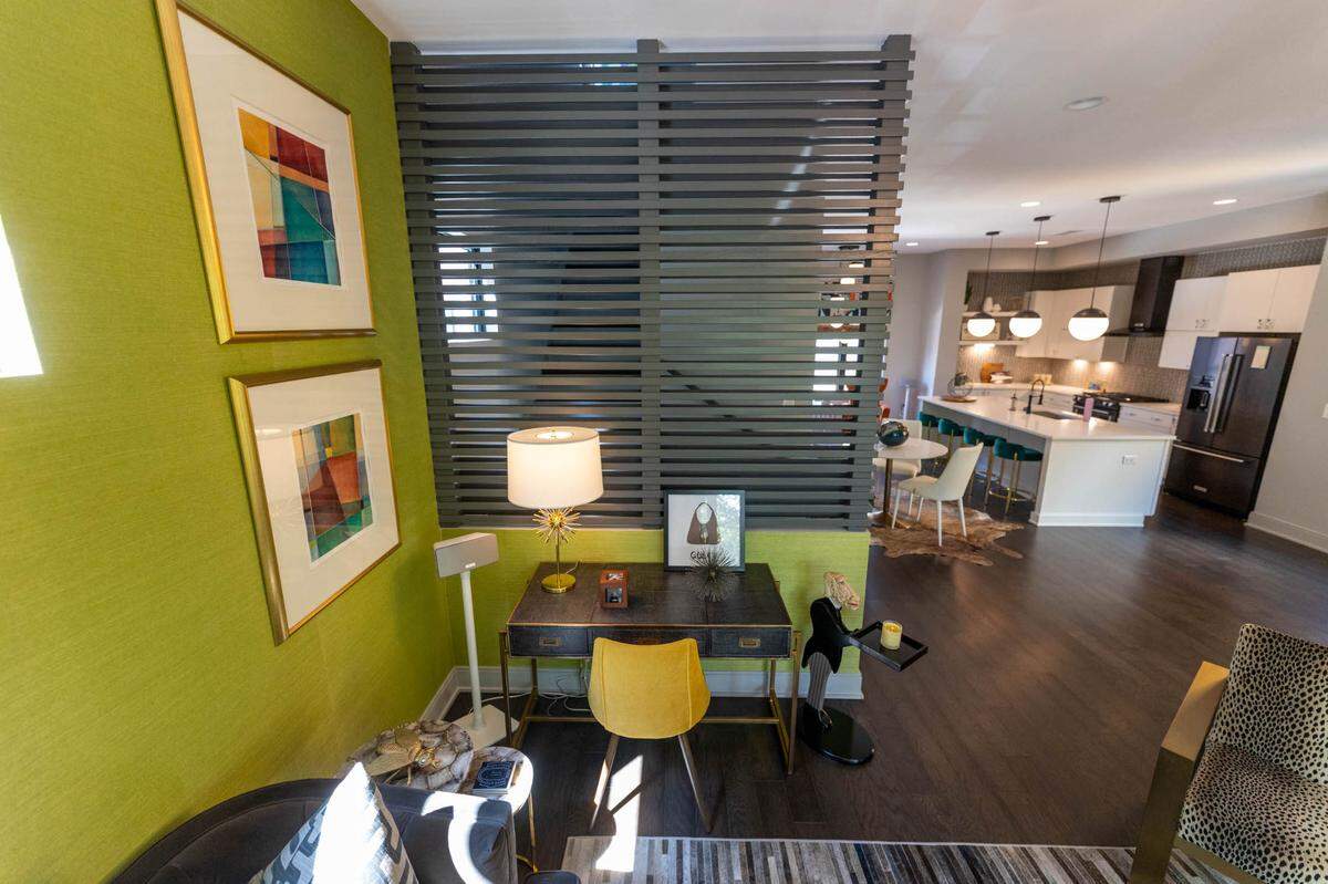 The home’s living room includes a bright green accent wall as its focal point. Check out the mini office in the corner.