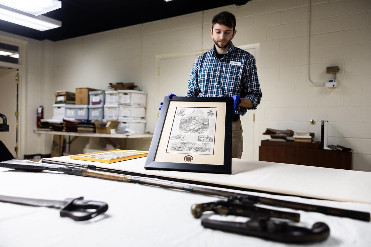 Kyle Booker, collections manager at the Charlotte Museum of History, displays an 1875 Harper's Magazine article magazine article about the 100th anniversary of the Meck Dec.