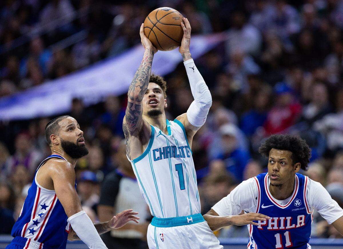 Charlotte Hornets guard LaMelo Ball (1) drives between Philadelphia 76ers forward Caleb Martin (L) and guard Jeff Dowtin Jr. (R) during the second quarter at Wells Fargo Center.