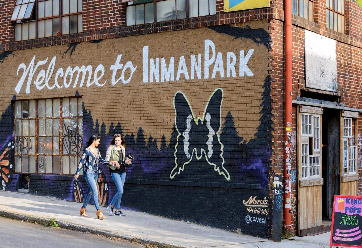 People stroll along a sidewalk in Inman Park in East Atlanta, past a mural by Chris Veal.