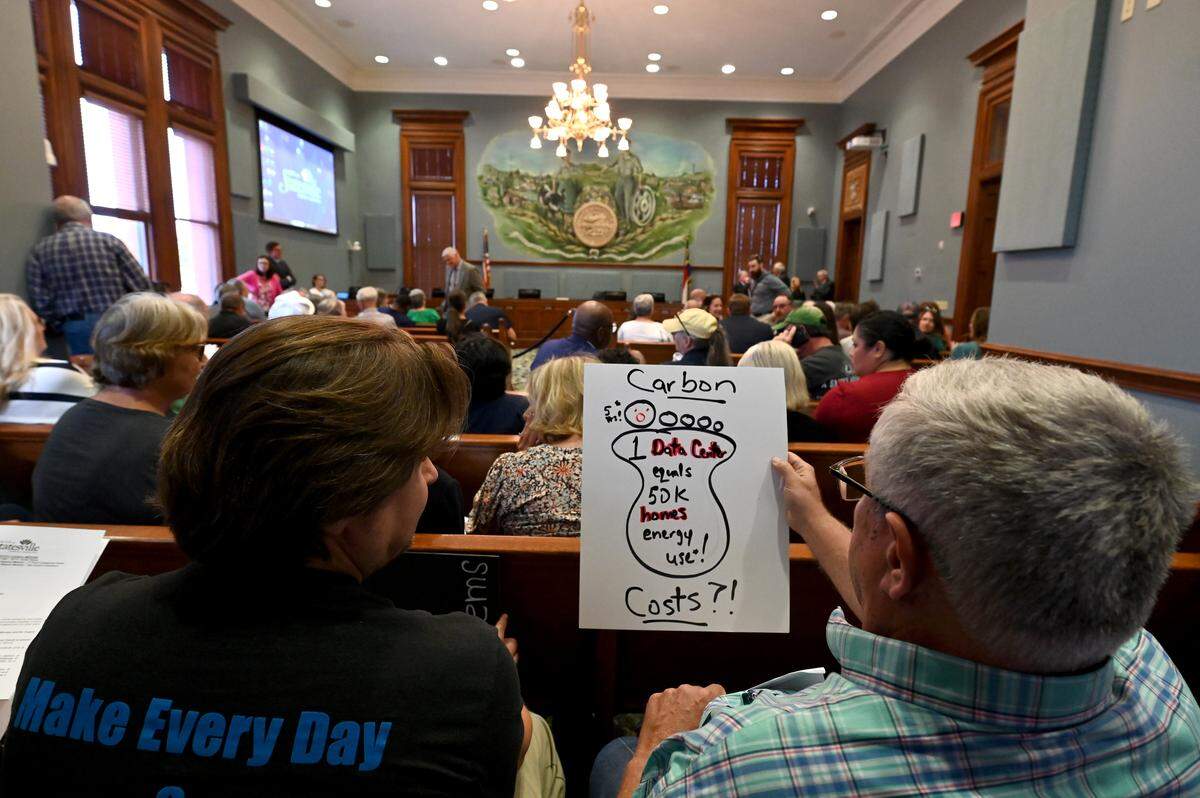 Residents look over a data center protest sign before a Statesville City Council meeting on Monday, Sept. 15, 2025.