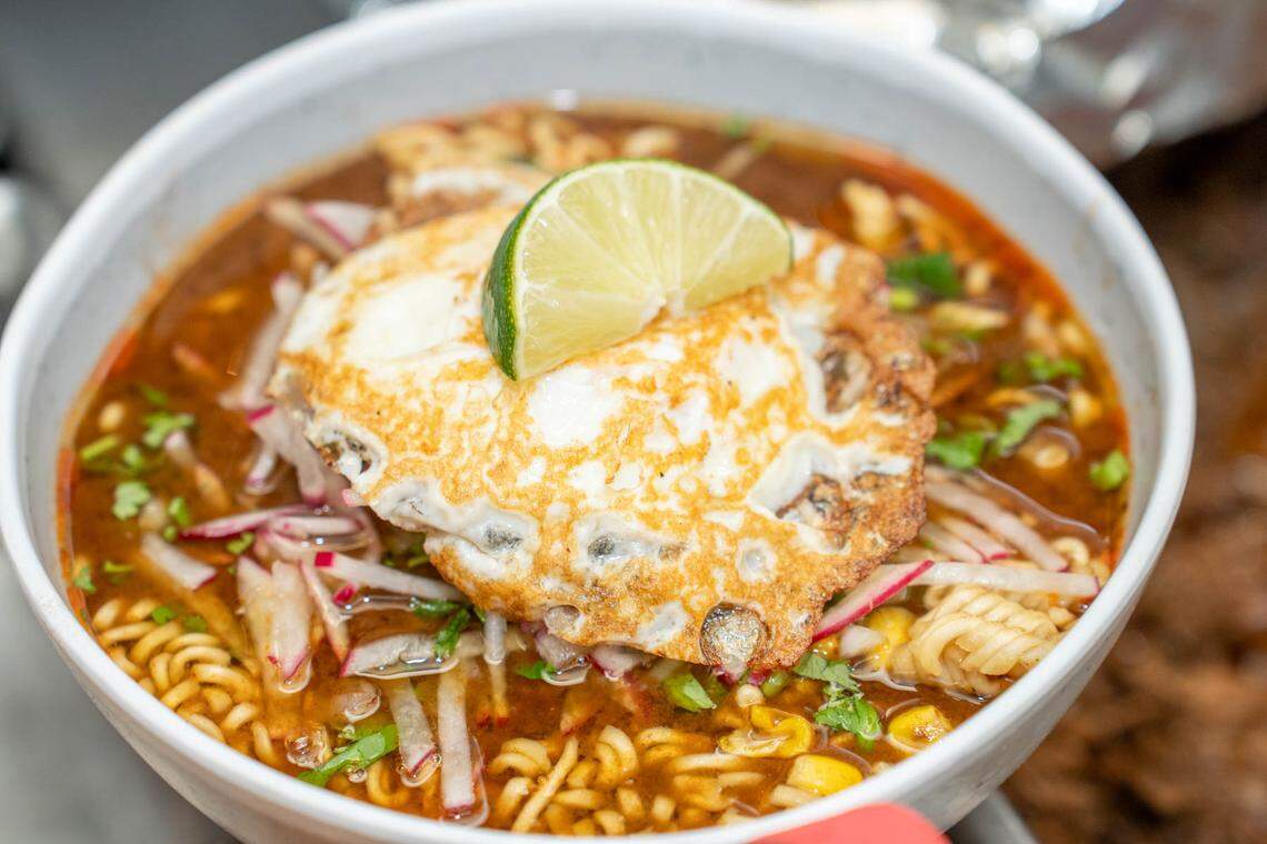 The Mexican Ramen at Birritaco includes Maruchan noodles cooked in birria broth, birria beef, onions, shredded radish, cilantro, roasted corn, green onions and an over-medium egg.