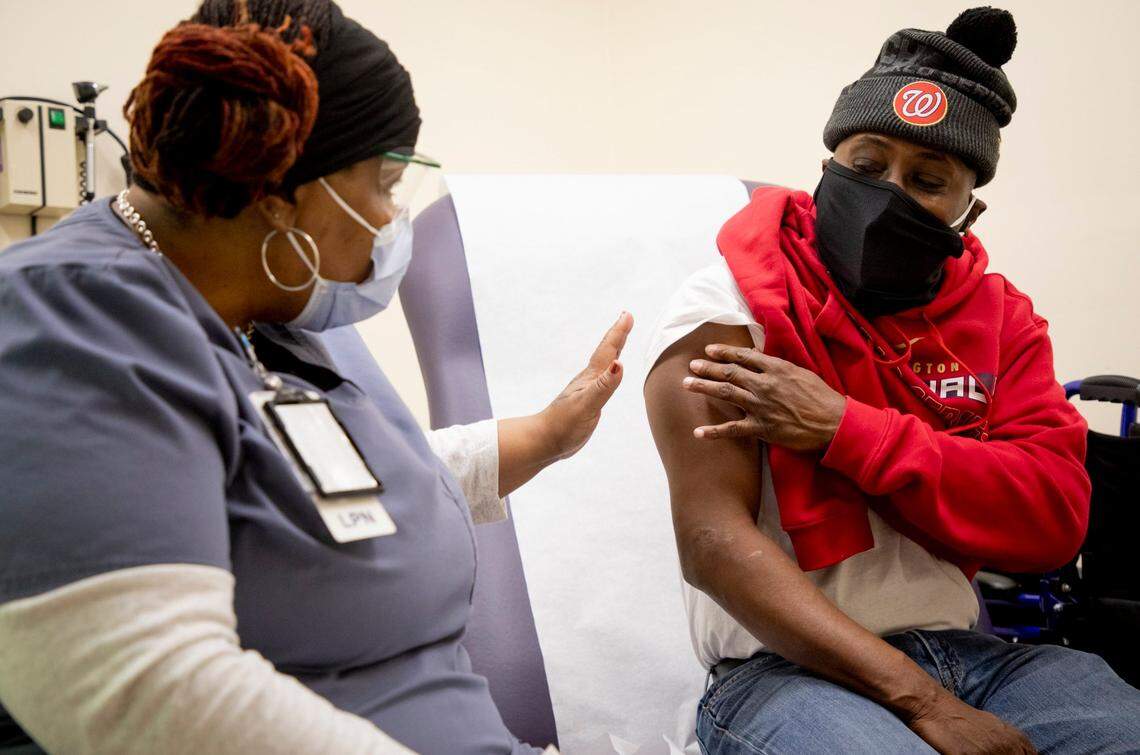 Licensed practical nurse Michele Vickers, left, helps Willard Hayes choose the best arm for his first dose of the Pfizer COVID-19 vaccine at the Durham VA Medical Center during a two-day mass vaccination event where they expected to inoculate 3,000 veterans, on Saturday, Feb. 6, 2021, in Durham, N.C.
